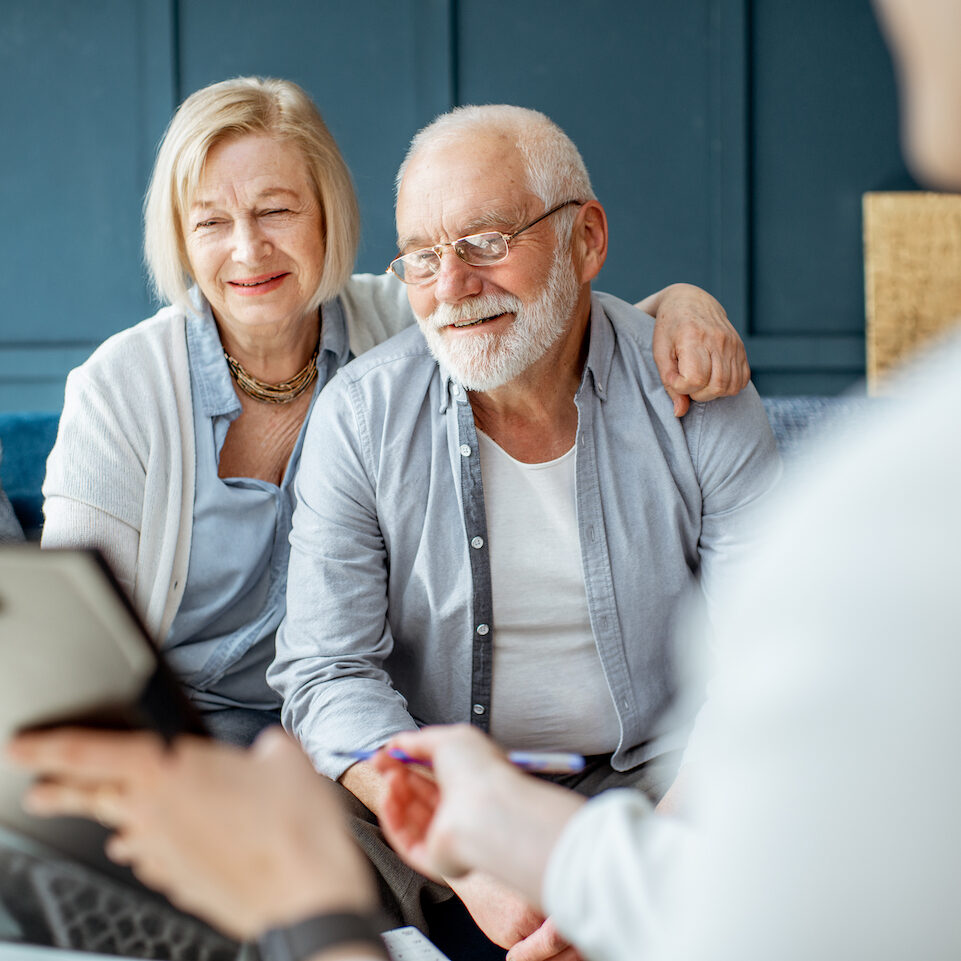 Happy senior couple during the meeting with agent or financial consultant, signing some agreement in the comfortable office