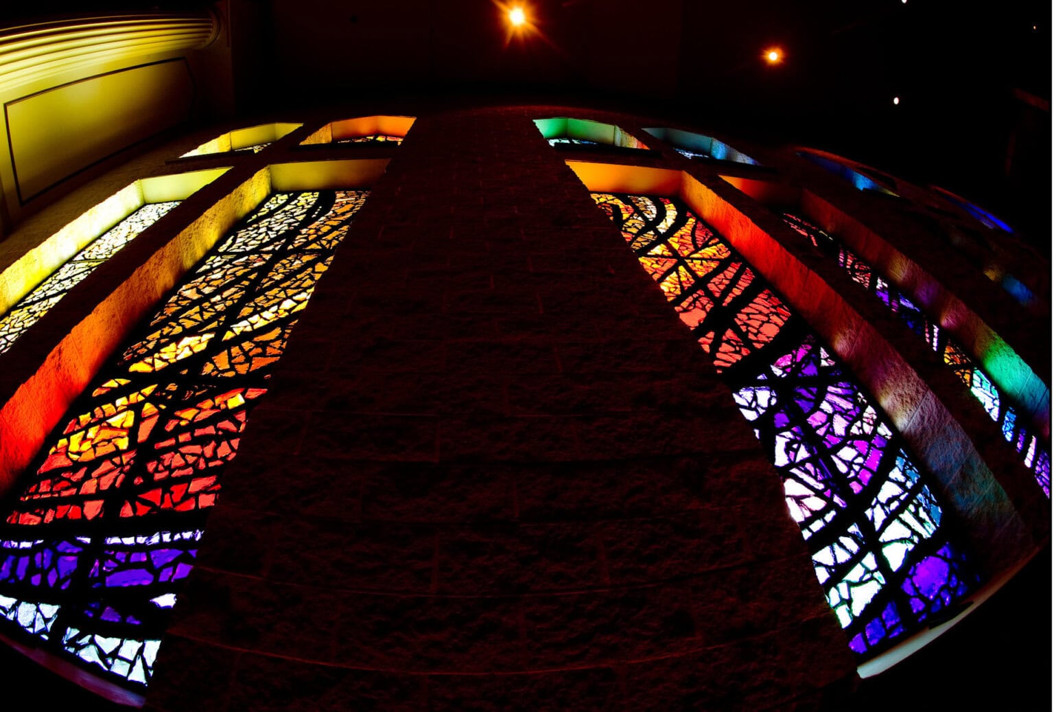 Vibrant stained glass window with colorful geometric patterns and a dark central pathway.