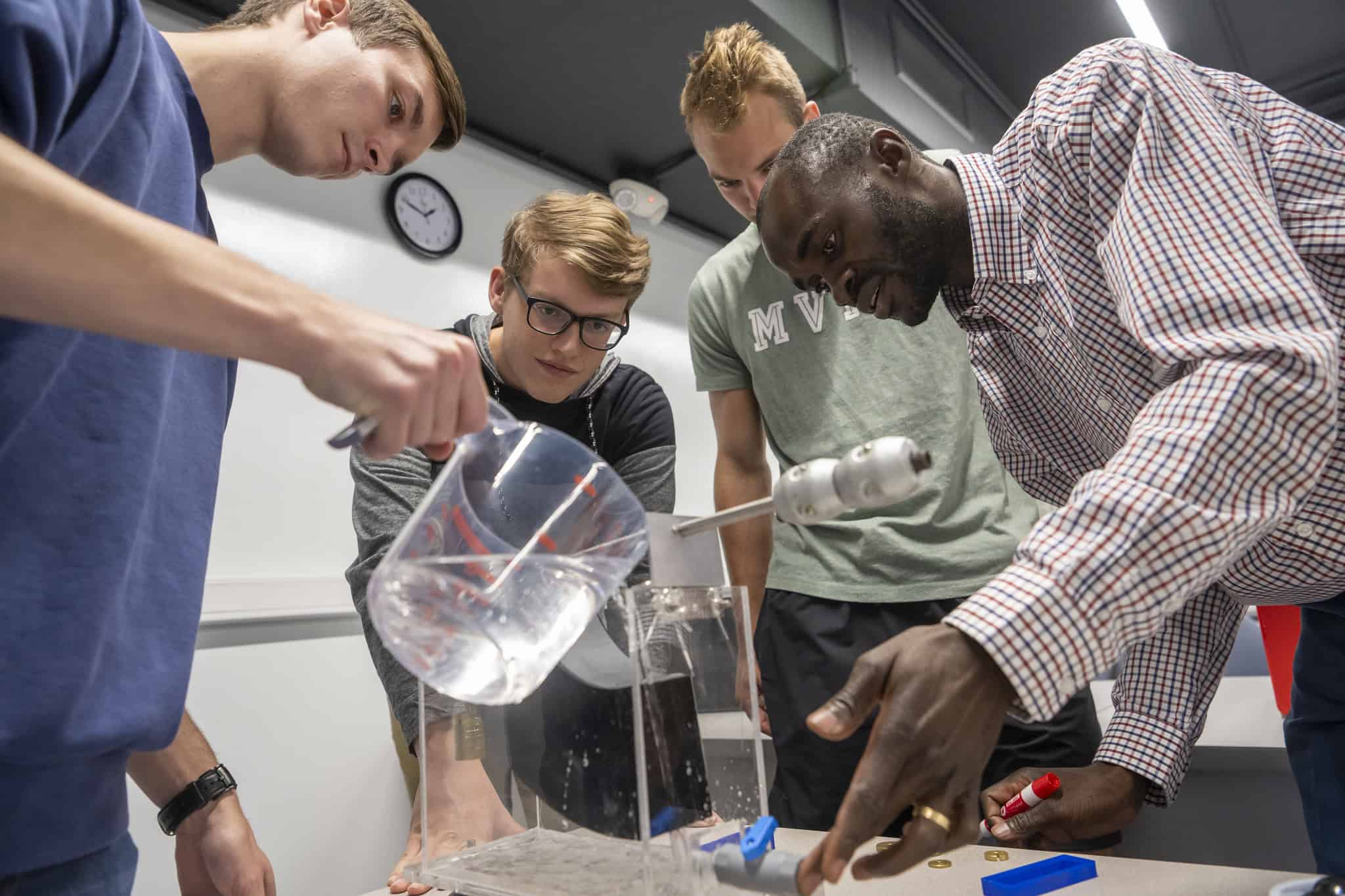 Water science experiment with diverse students in a classroom.