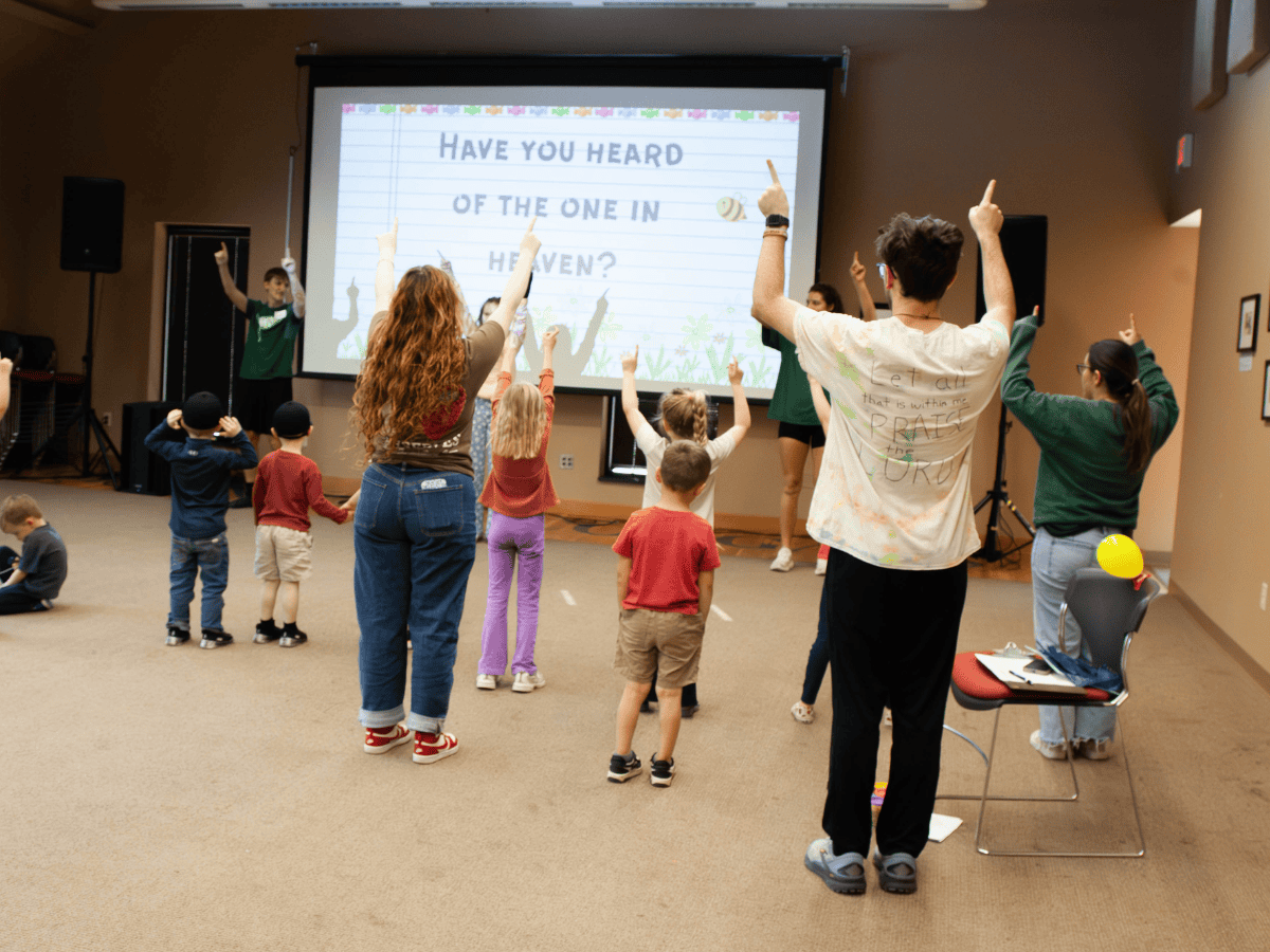 Children participating in a church activity with raised hands during a pastoral ministry event.