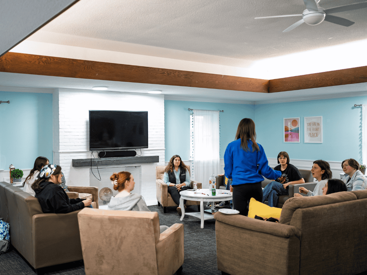 Women and men participating in a Christian ministry group discussion in a cozy living room.