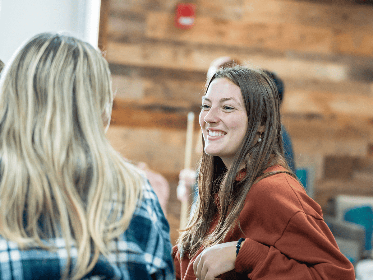 Two women engaged in a friendly conversation in an educational setting.