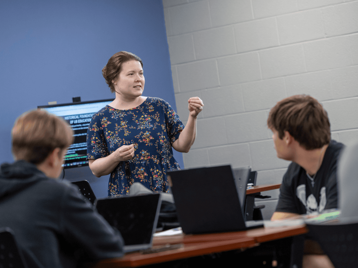 Teacher leading a discussion with students in a classroom setting.