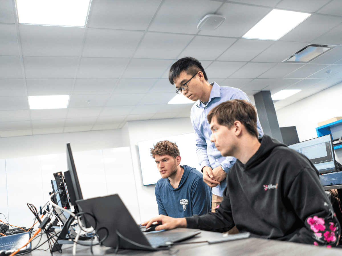 Young men collaborating on computer programming project in a tech office.