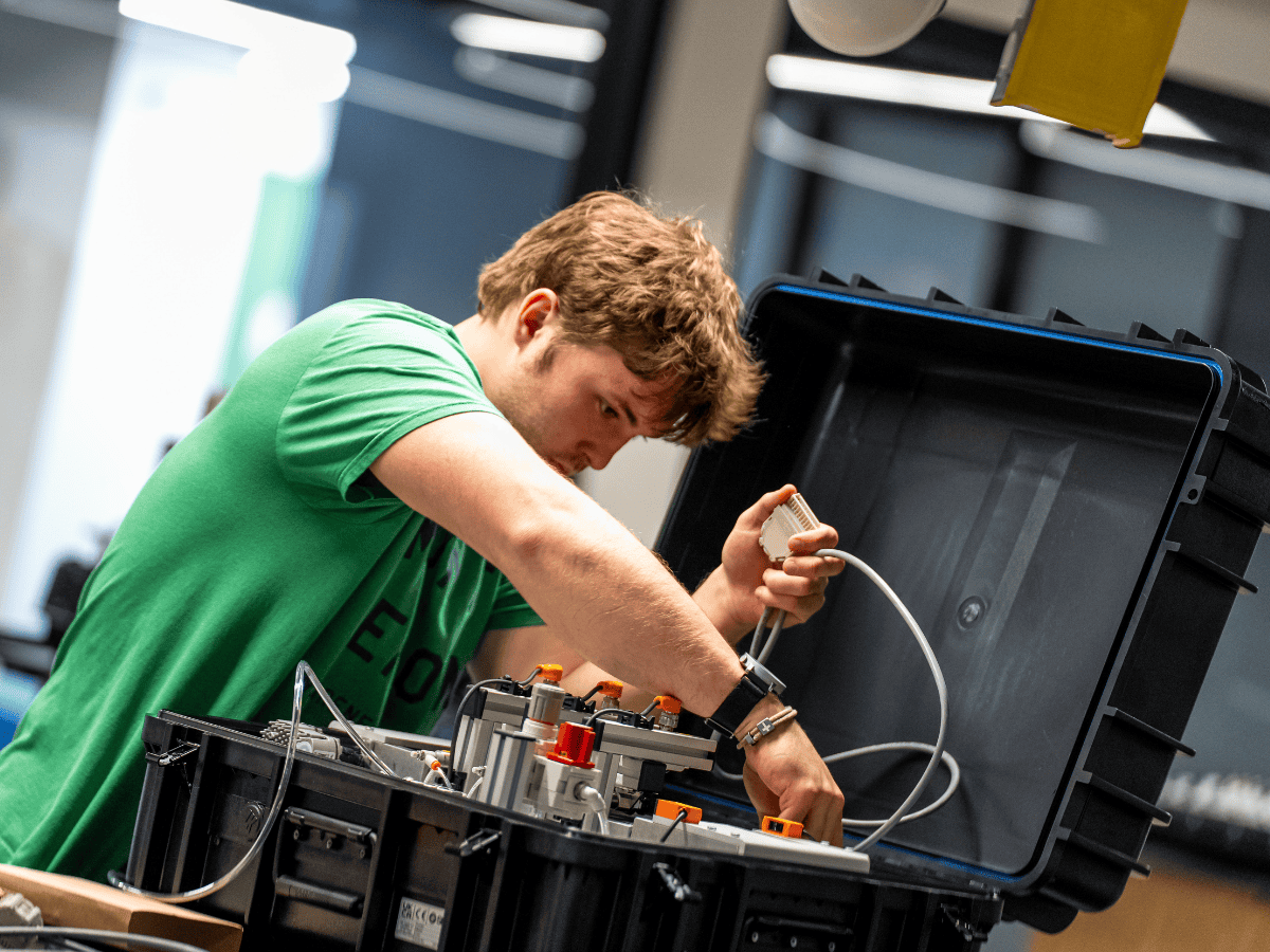 Young man troubleshooting electronic components in a tech lab.
