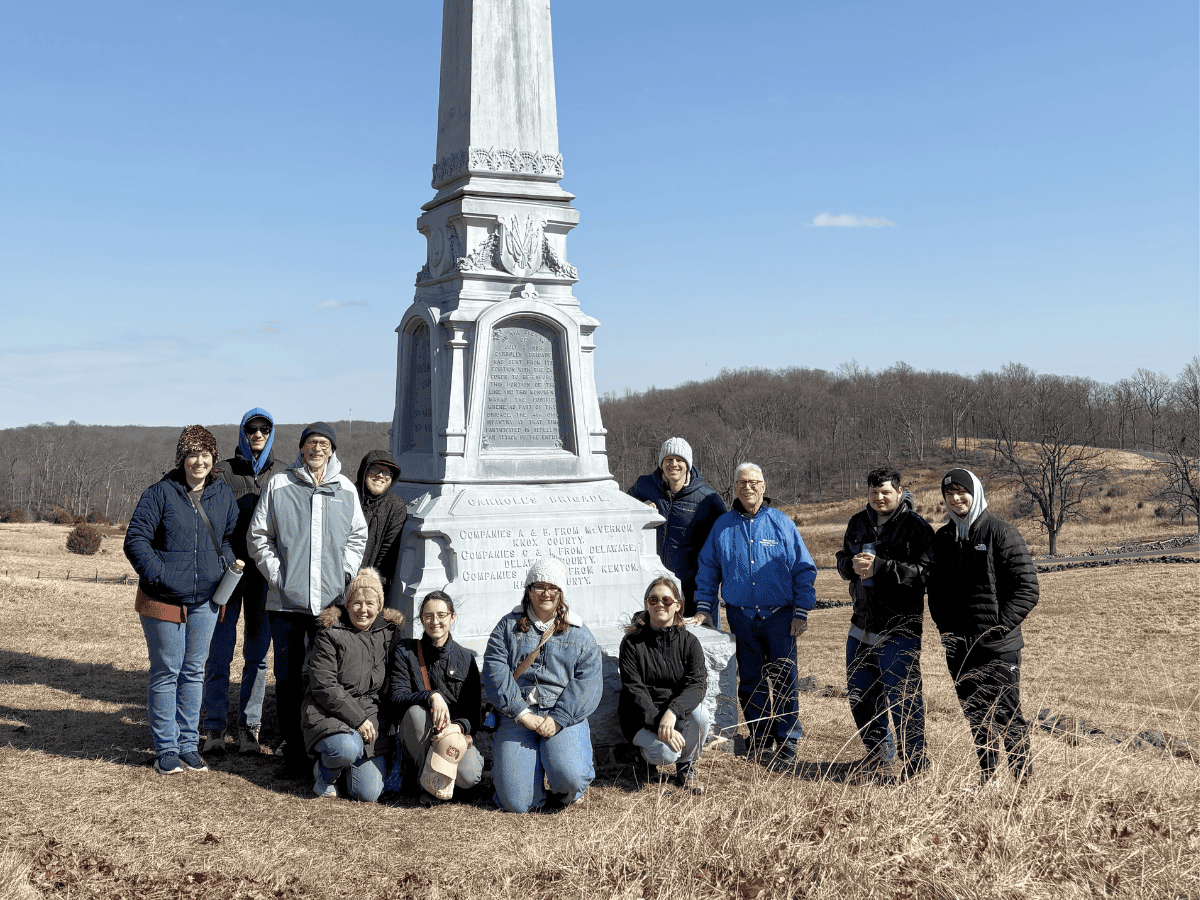 Group of people visiting a historic monument in an open field.