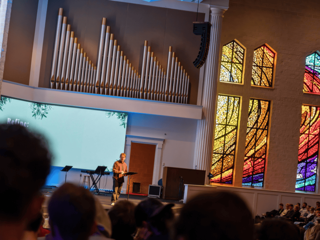 Interior of a church with a large pipe organ and colorful stained glass windows.