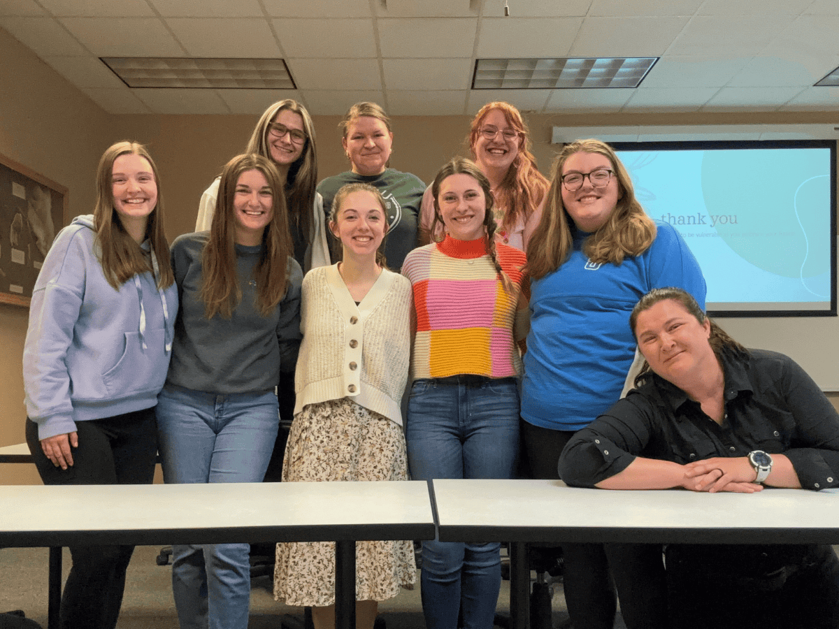 Volunteers group photo at a community event, smiling and standing together indoors.