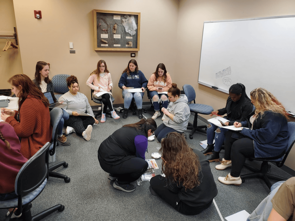 Group of students and teacher in classroom participating in a learning activity.
