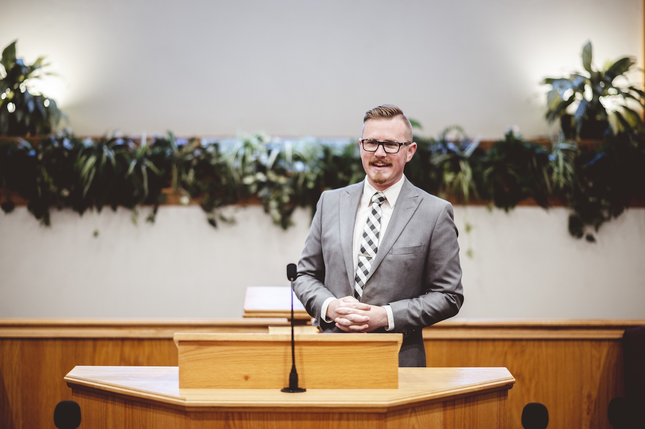 Male in a formal outfit preaching the Holy Bible from the tribune at the altar of the church Church pastor