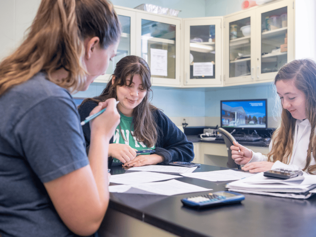 Students collaborating on schoolwork at a table with educational materials.