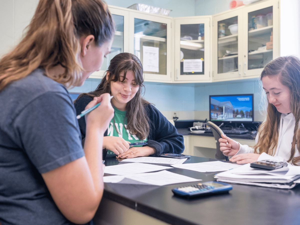 Students collaborating on schoolwork at a table with educational materials.