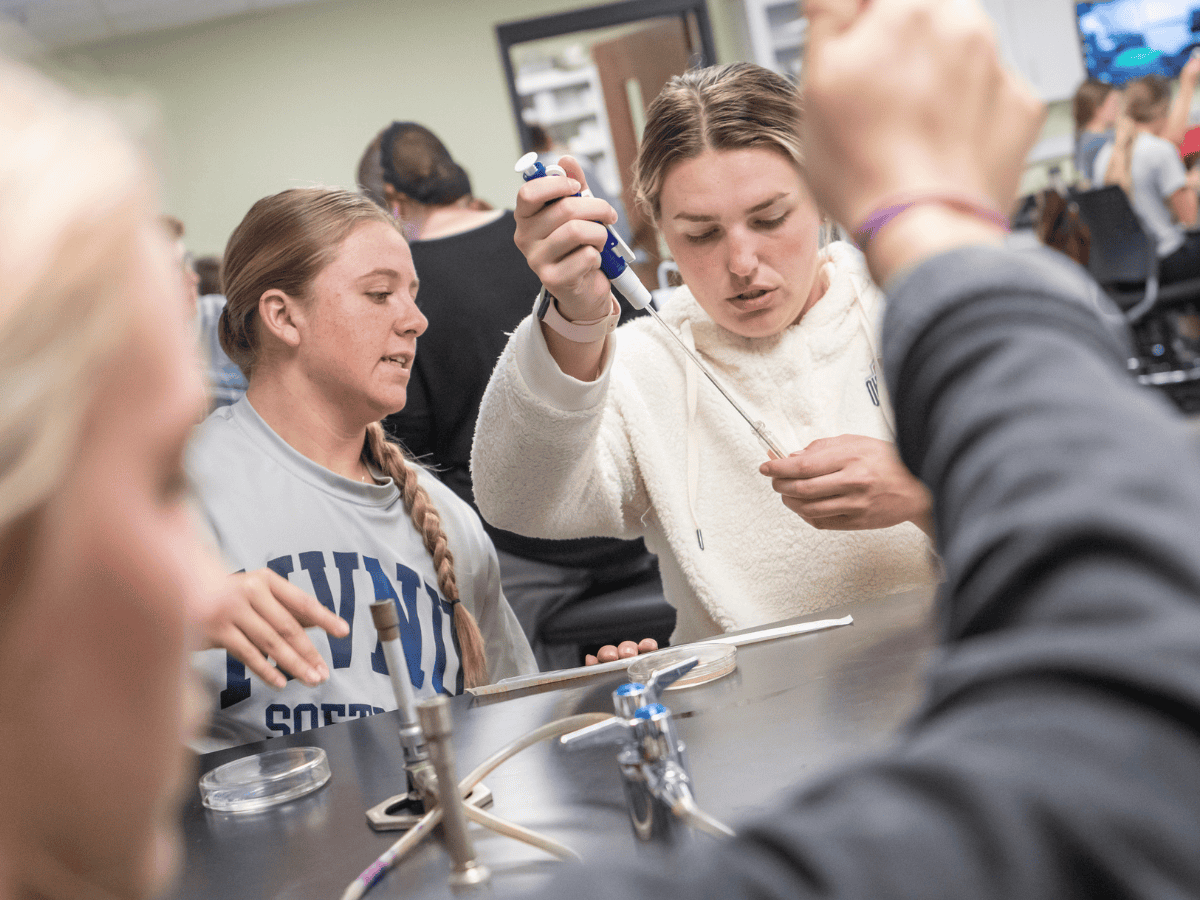 Students conducting a science experiment with test tubes and safety equipment.