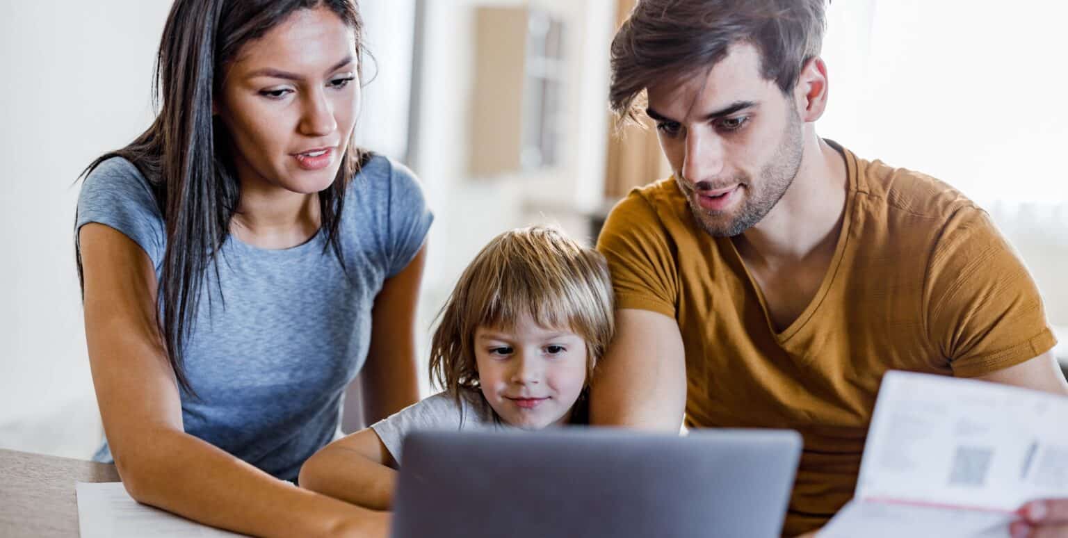 Woman and family juggling life’s responsibilities, such as reviewing bills, while pursuing an online education at MVNU, on a laptop at home