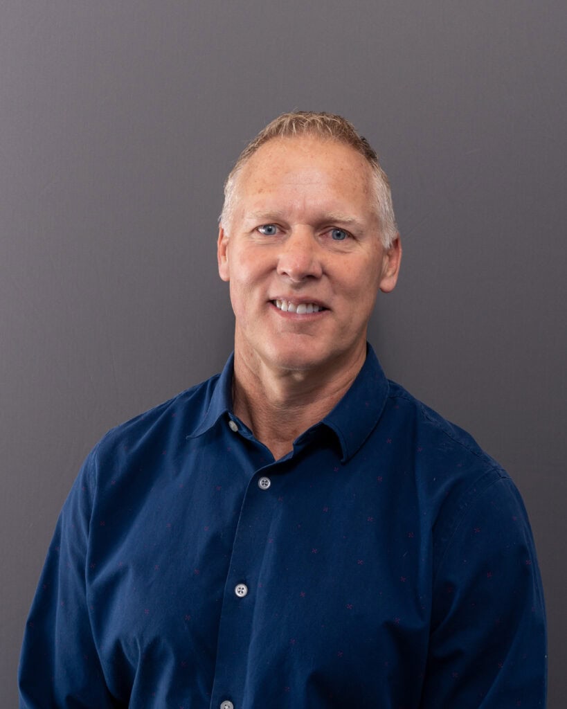 Professional man in blue shirt smiling against gray background, portrait for business or corporate w.
