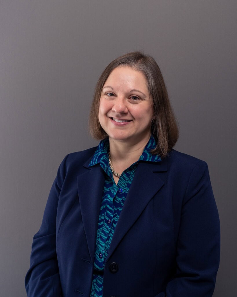 Experienced professional woman in business attire smiling at the camera.