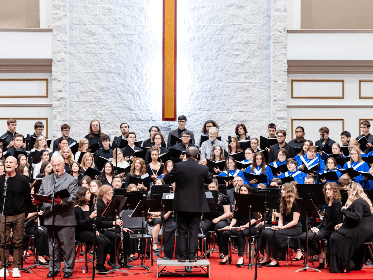 A musical orchestra performing on stage with a conductor leading.