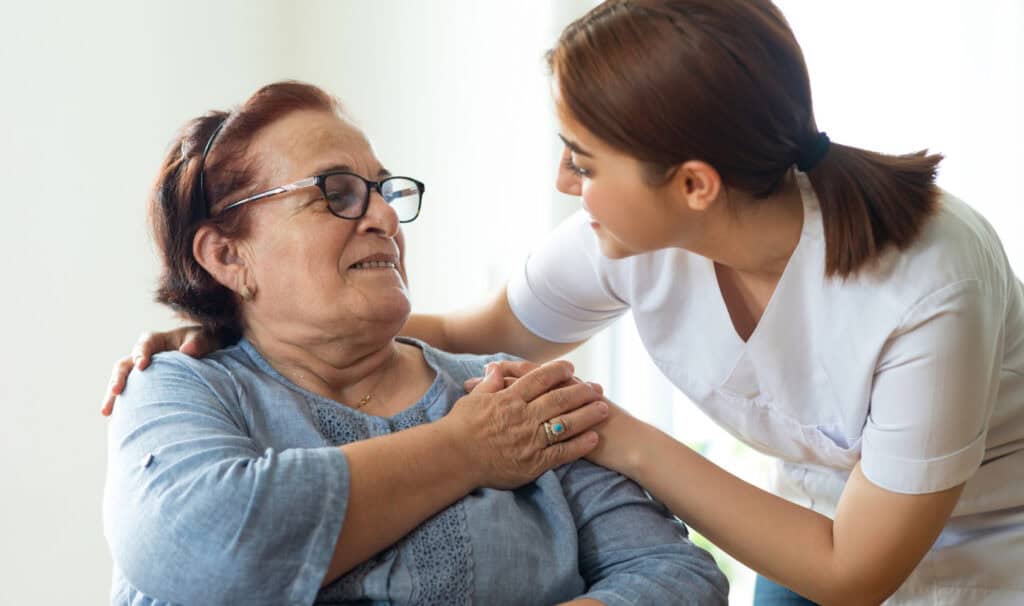 A compassionate healthcare professional gently supports an elderly woman in a wheelchair, reflecting the kind of care and advocacy taught in MVNU’s online Social Work programs.