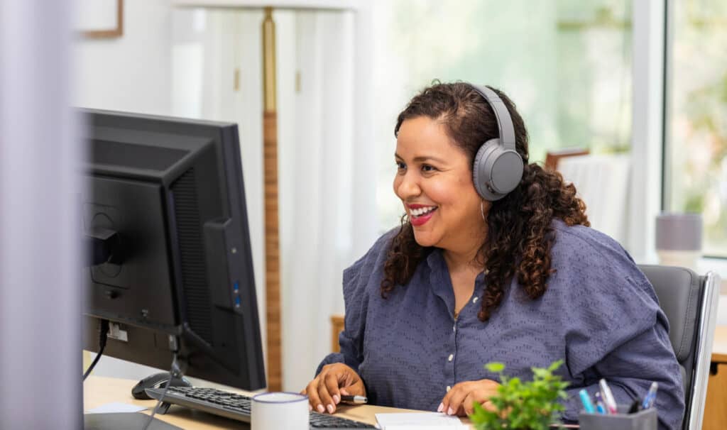 Adult student wearing headphones smiles while taking an online class at home, representing MVNU’s flexible, accredited online programs that prepare students for real-world career success.