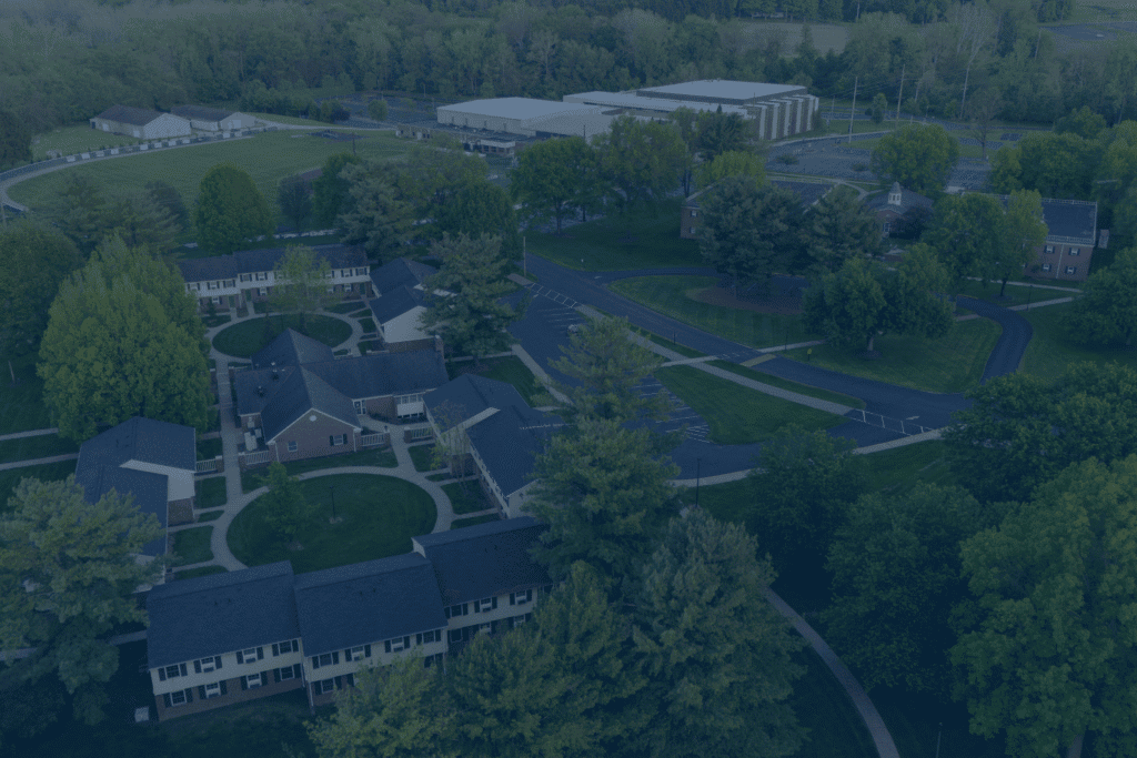 Aerial view of a school campus surrounded by trees and sports fields.