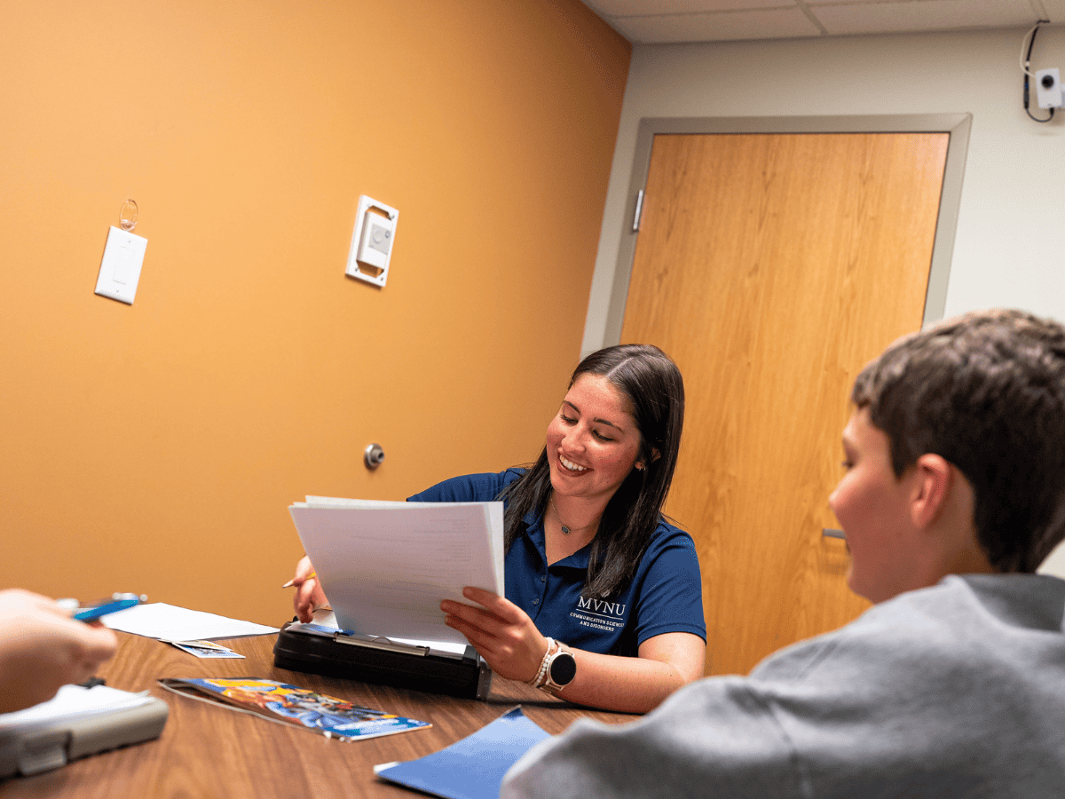Student and instructor in speech-language pathology class discussion.