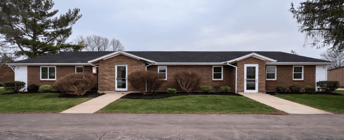 Apartment complex with brick exterior, multiple entrances, and landscaped lawns.