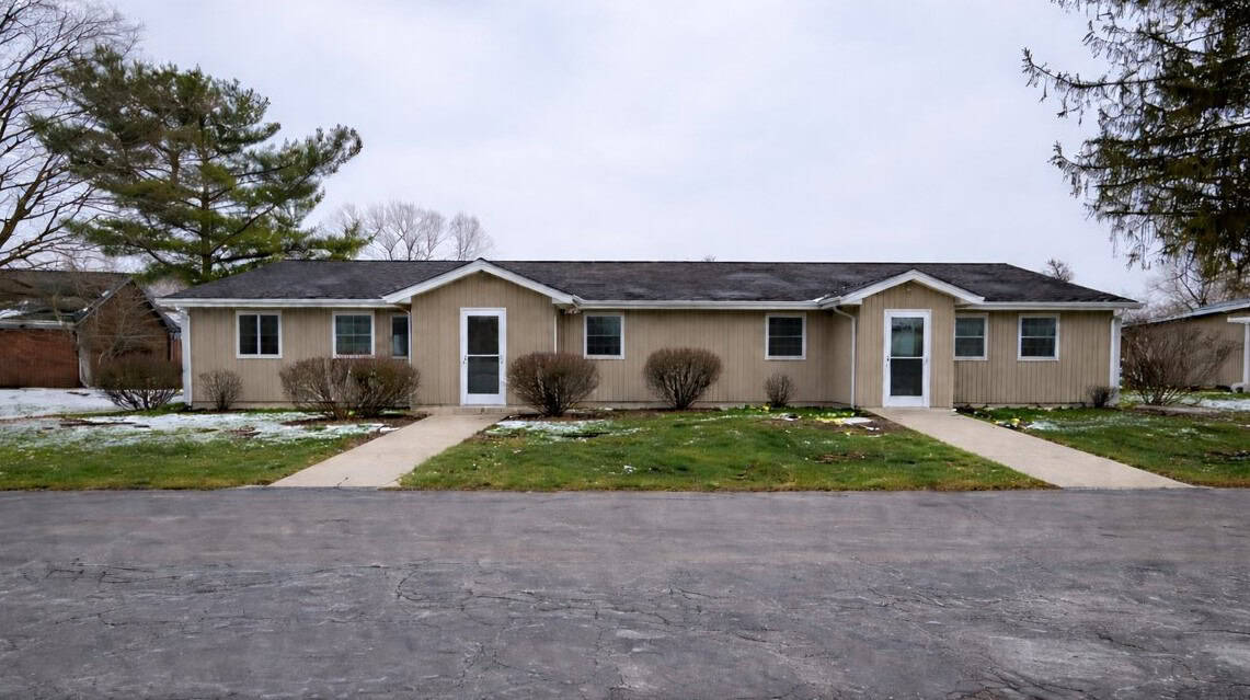 Cozy beige single-story residential building with front yard and pathways.