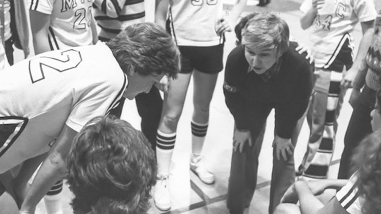 Volleyball coach with team during game at MVNU.