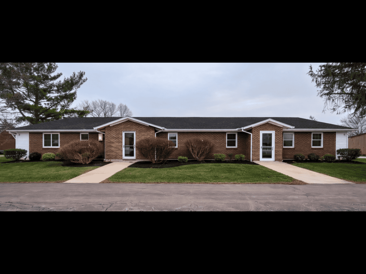 Single-story brick house with landscaped yard and sidewalk.