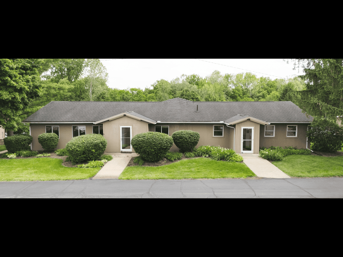 Duplex home with well-maintained front yard and bushes, situated in a peaceful neighborhood.