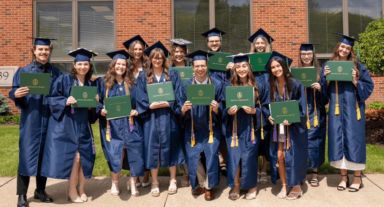 Group of diverse graduates in caps and gowns celebrating graduation.