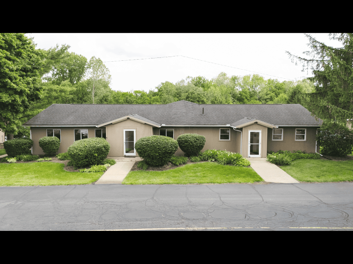 Single-story residential building with well-maintained bushes and lawn.