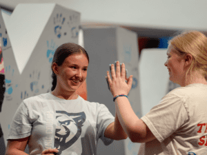 Two young women high-fiving at New Student Orientation event.