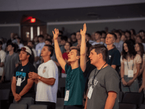 Students at orientation event raising hands and engaging in activities.