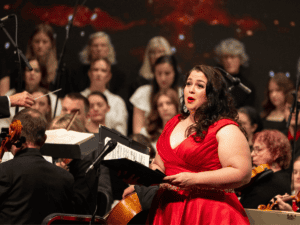 Female soloist singing with orchestra and choir at MVNU concert.