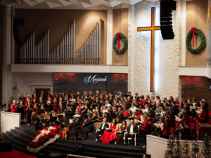 Choir and orchestra performing Handel’s Messiah in a church with Christmas wreaths and cross.