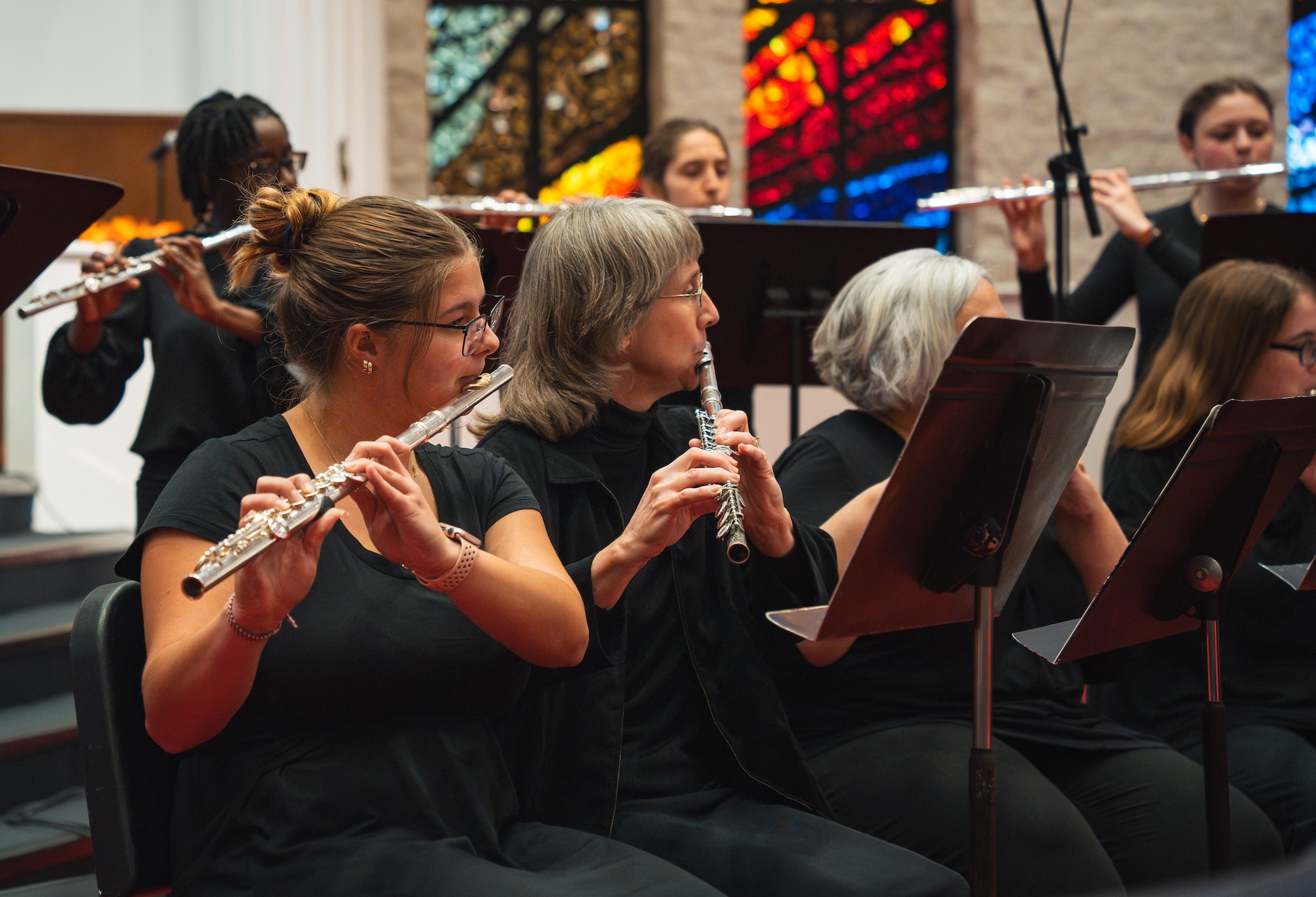 Musicians playing flutes during a concert in a church setting.