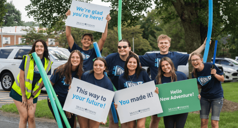 Group of MVNU students holding signs smiling and celebrating move-in day.