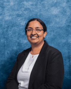 Professional portrait of Dr. Sandra Richy John with glasses and a black blazer.