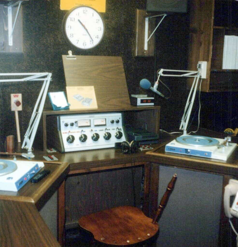 Radio station studio with turntables, microphones, and control panel.