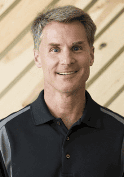 Smiling male speaker in black polo shirt at conference event.