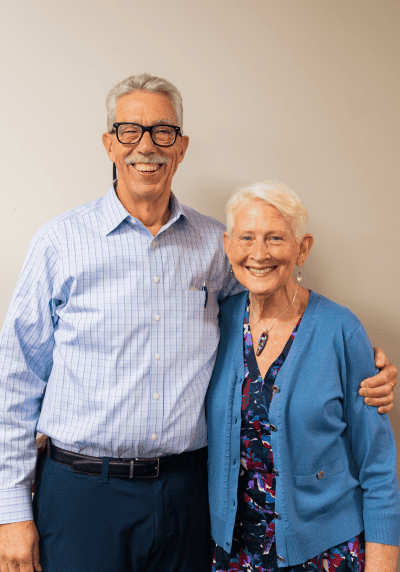 Smiling senior man and woman standing together, embracing, at a social event.