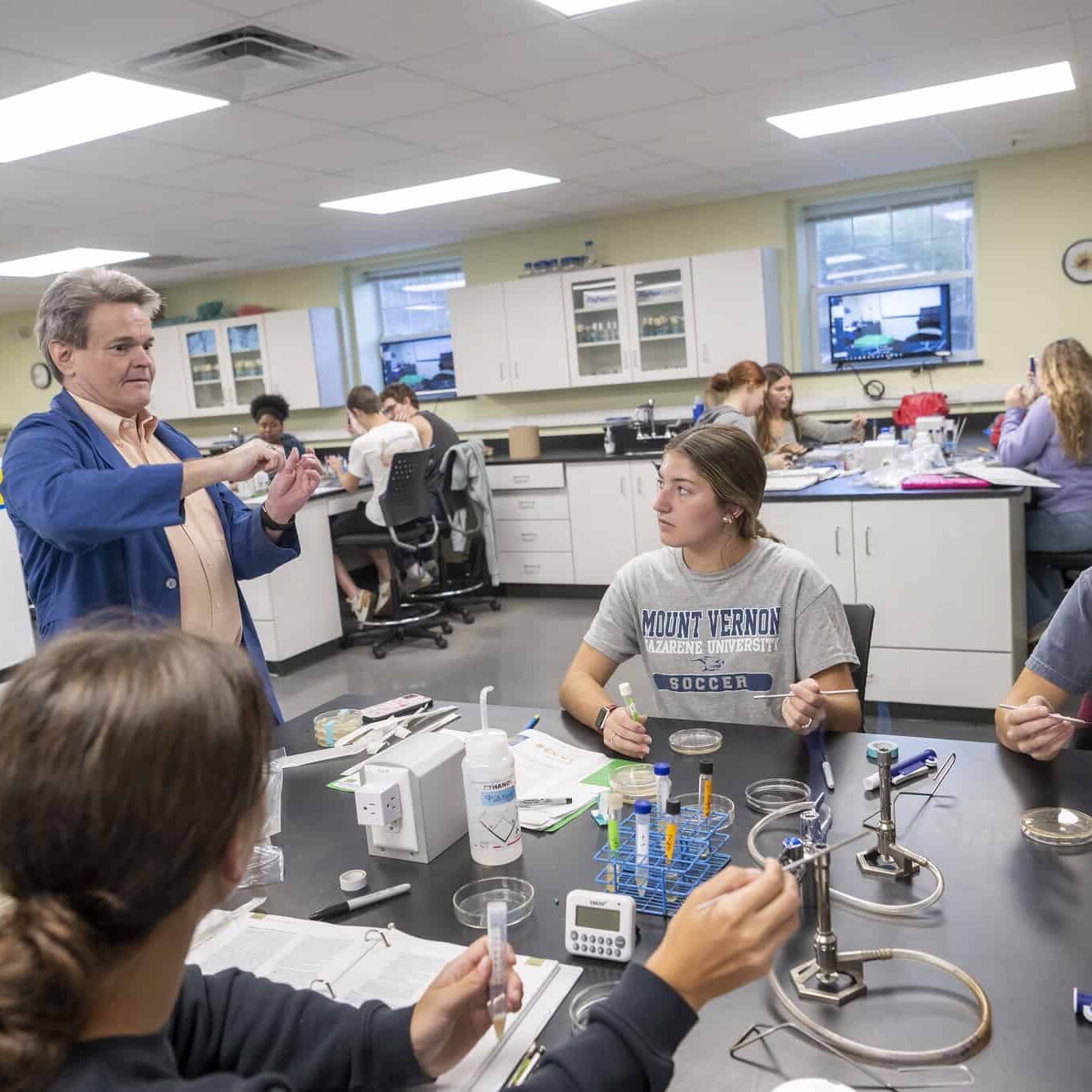 A science teacher demonstrating an experiment to students in a laboratory classroom.