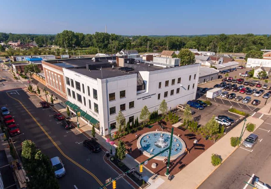 Downtown commercial building with a fountain and parking lot, aerial view.