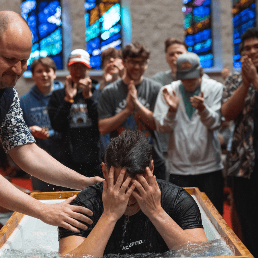 Comforting a person during baptism ceremony in church with stained glass windows.