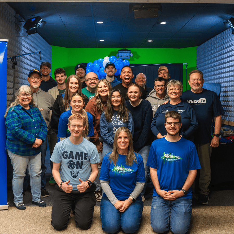 WNZR radio station team group photo in studio with green screen background and blue balloons.