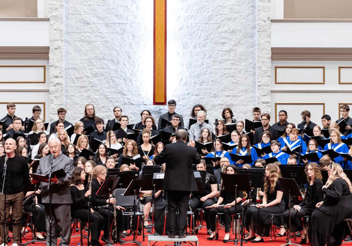 A musical orchestra performing on stage with a conductor leading.