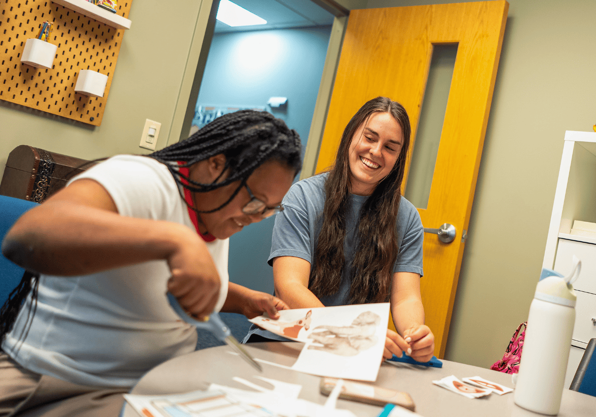 Young women collaborating on artwork in a creative office space, smiling and sharing ideas.