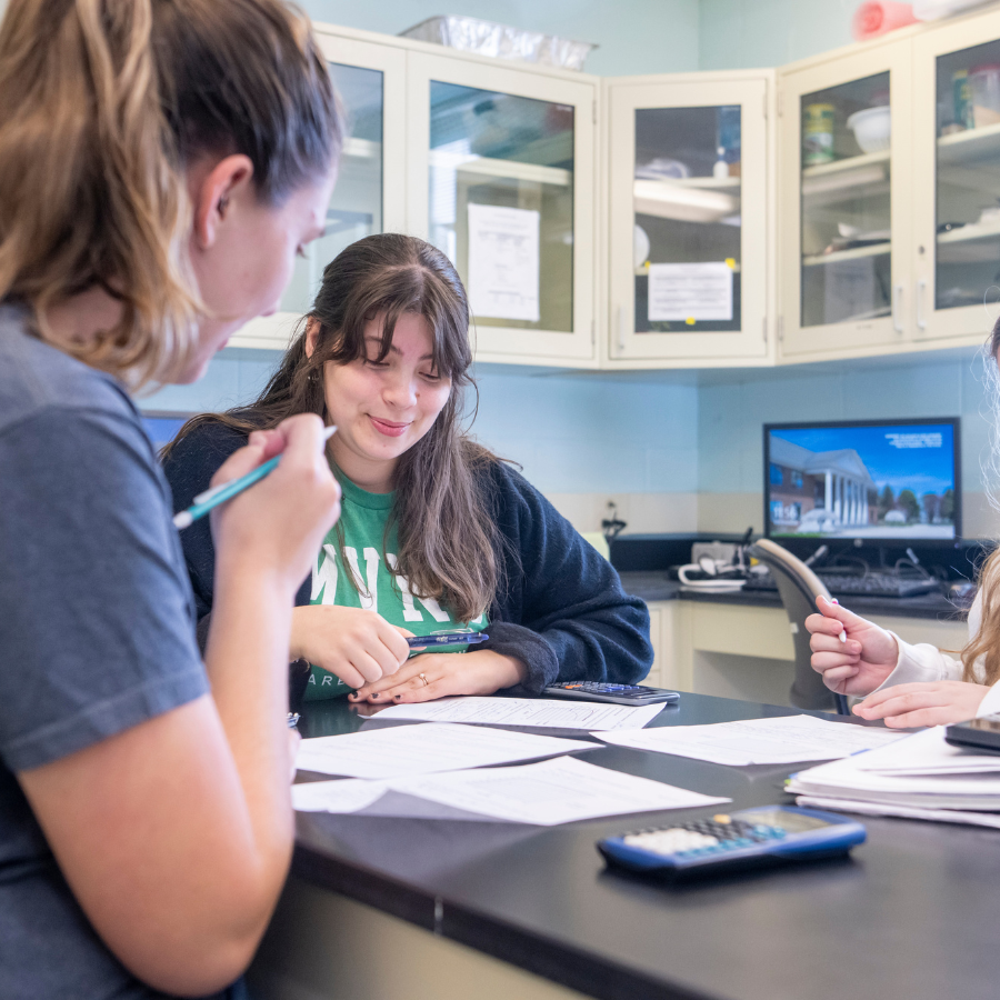 Students collaborating on schoolwork at a table with educational materials.