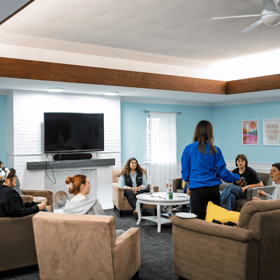 Women and men participating in a Christian ministry group discussion in a cozy living room.